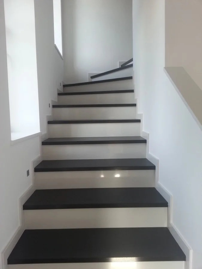 Moderne weiße Innentreppe mit dunklen Natursteinstufen